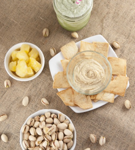 Pistachios, Pineapple bits, hummus and pita chips, and a green tea drink for perfect healthy snacking.