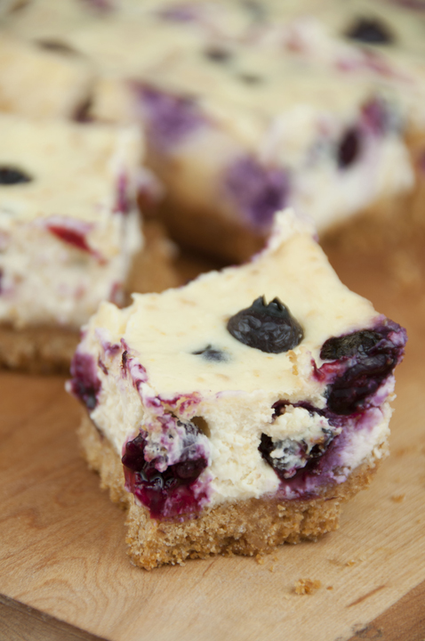 Creamy lemon cheesecake bars recipe swirled with blueberries on a simple graham cracker crust.
