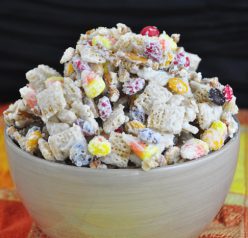 A new twist on party snack mix includes white chocolate, chex cereal, fall M&M's, candy corn, and pretzel sticks for a Halloween dessert.