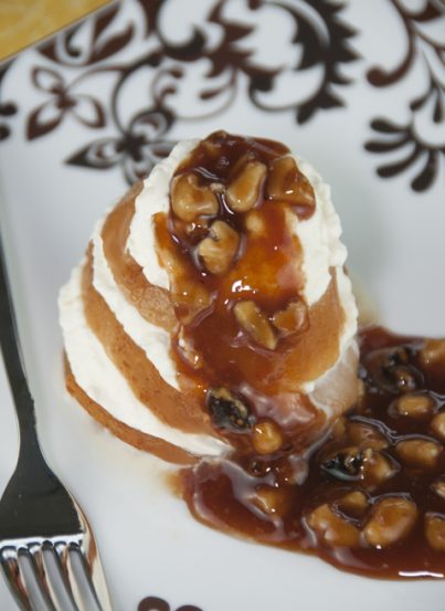 A simple recipe for poached pears in orange juice and topped with cinnamon syrup and walnuts.