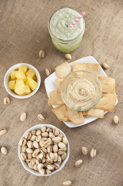 Pistachios, Pineapple bits, hummus and pita chips, and a green tea drink for perfect healthy snacking.
