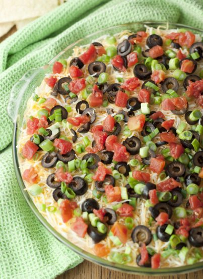 This dip has so many colorful layers of deliciousness. Refried beans, guacamole, sour cream, cheese, spicy tomatoes, olives and green onion make for the perfect party or game day appetizer.