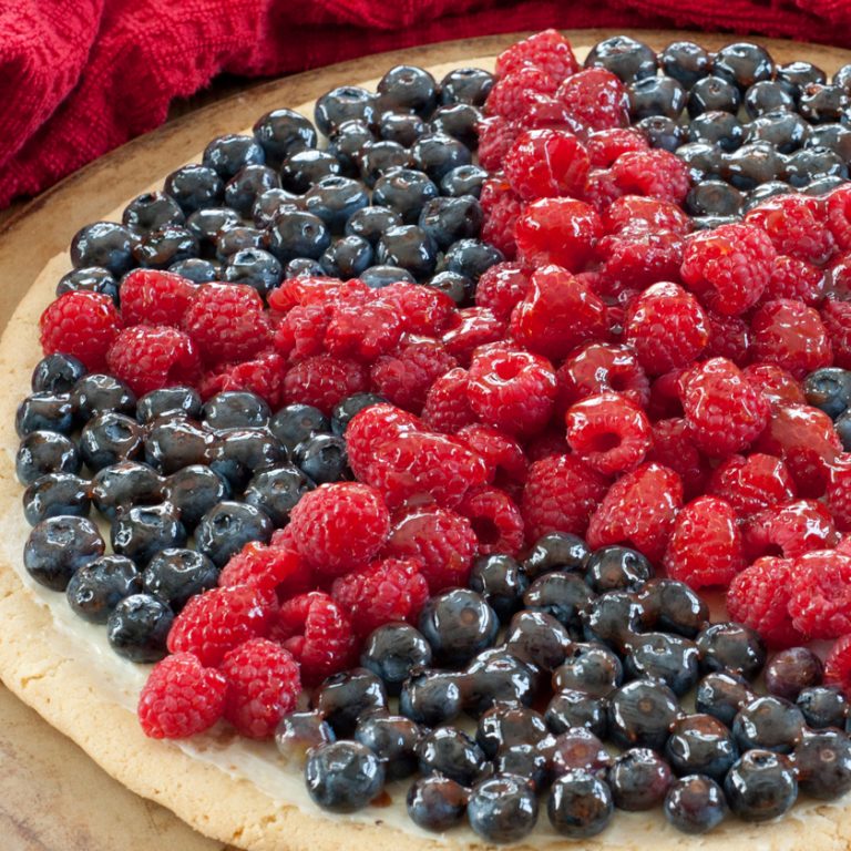 Easy Red, White, and Blue Patriotic Sugar Cookie Fruit Pizza dessert recipe will be the star of the show at your summer 4th of July party! It is made with refrigerated cookie dough.