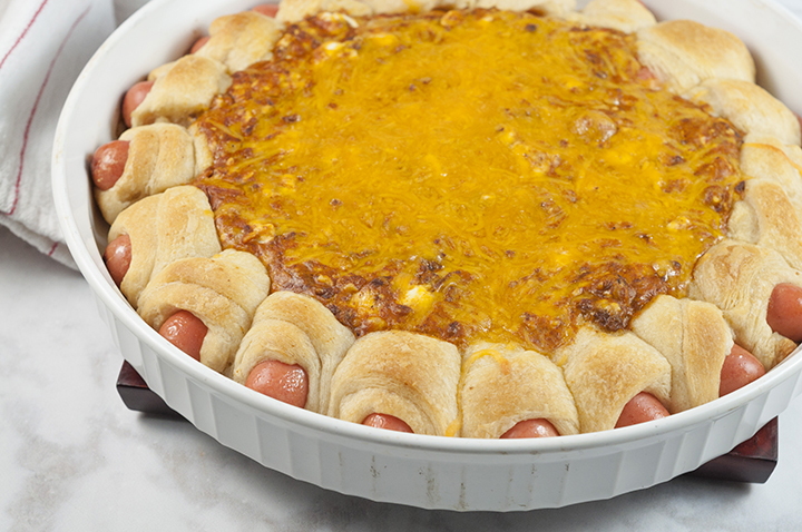Chili Cheese Dog Wreath Dip recipe combines a cheesy, chili dip surrounded by perfectly baked pigs in a blanket for a show-stopping dip at your next party, holiday or Super Bowl!