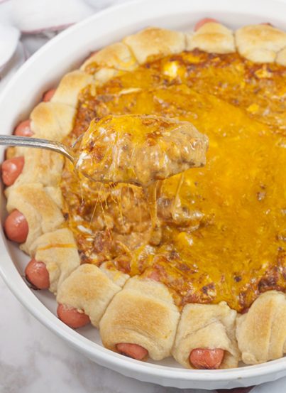 Chili Cheese Dog Wreath Dip appetizer recipe combines a gooey, cheesy, chili dip with cocktail wiener "pigs in a blanket" for the best dip at your next party, holiday or Super Bowl!