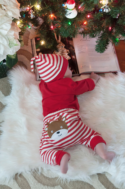 Baby Eliza reading a book under the Christmas tree.