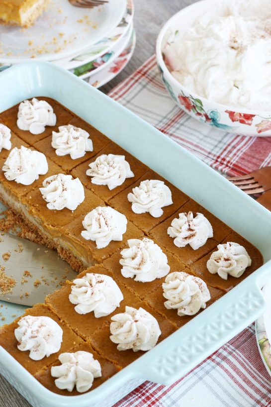 A pan of pumpkin cheesecake bars with a few servings removed.