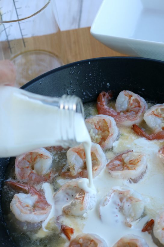Image shows the cream being added to the shrimp with garlic sauce recipe. The next step for how to cook shrimp with garlic butter sauce!