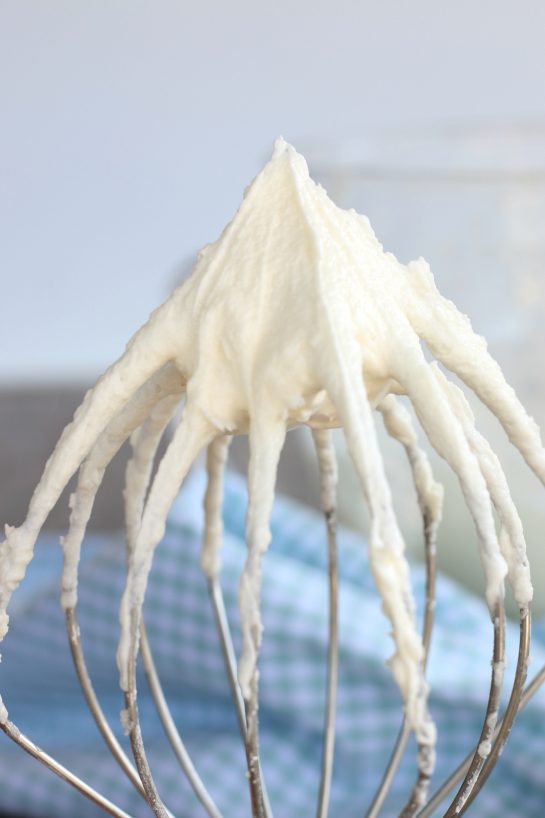 The best buttercream frosting recipe is in finished and being shown stuck to the whisk!