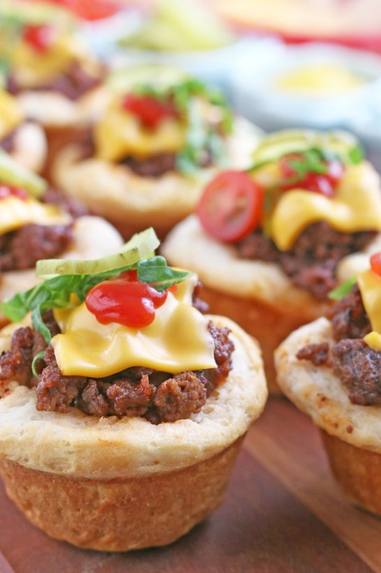 Here we see the finished cheeseburger biscuit bites finished and topped with veggies to eat! Great for Super Bowl appetizer!