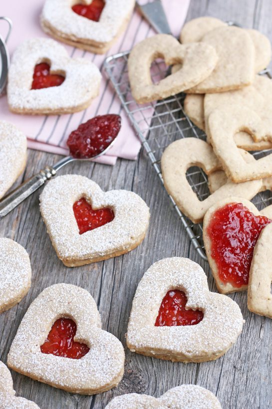 A close up shot of the finished recipe for linzer cookies with jam being added and cookie tops being assembled.