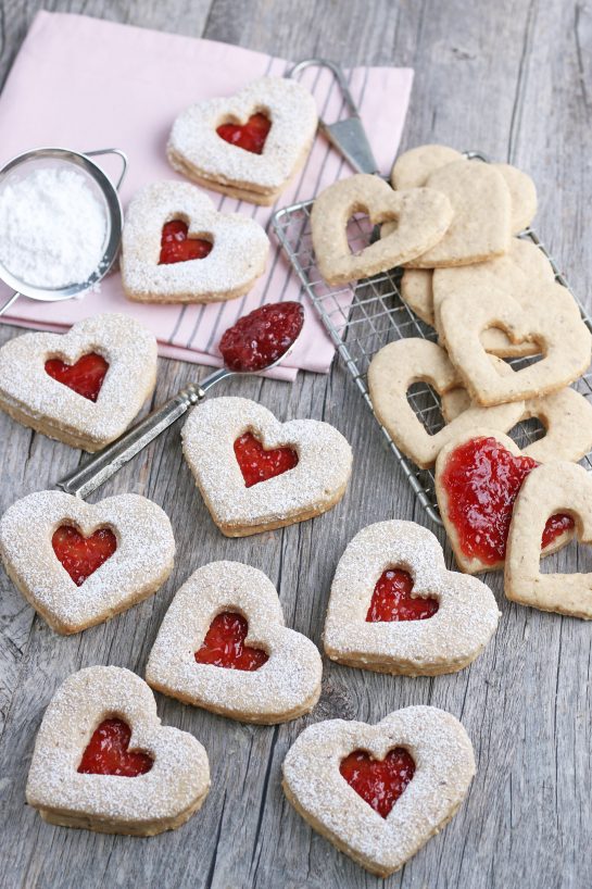 Here we see the heart shaped cookies some are finished and some Linzer cookies are being assembled in the background.