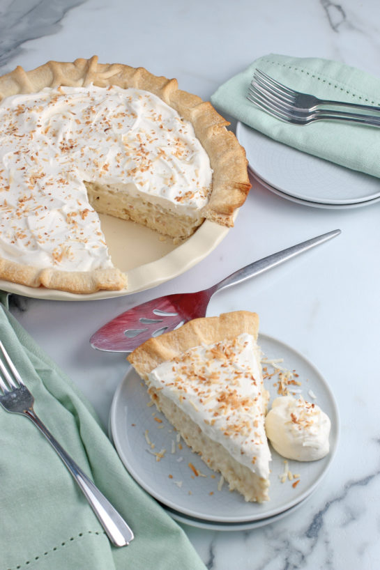 This view shows the slice of pie on a plate with the rest of the coconut cream pie in the background to share.