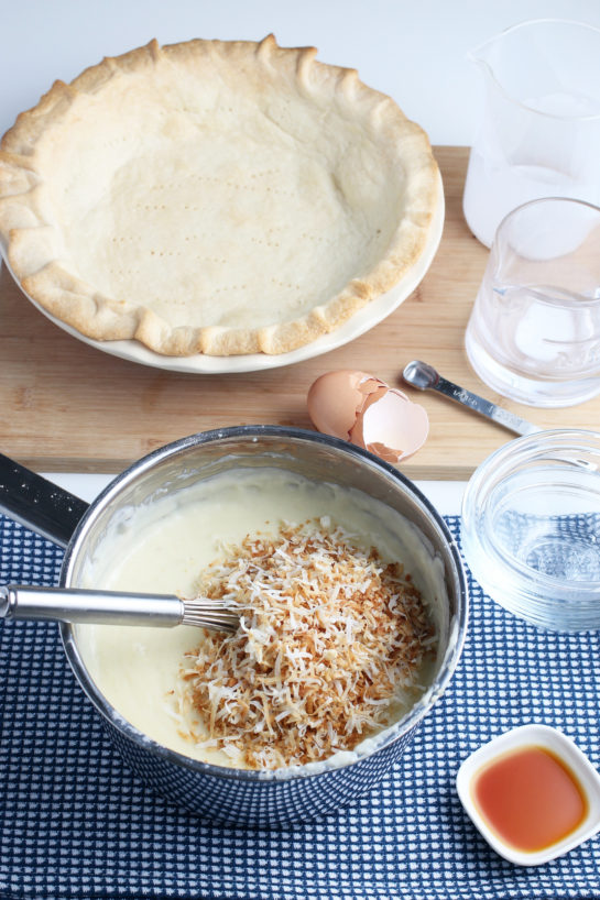 Here we see the toasted coconut being added to the mixture for the custard filling for the best coconut cream pie.