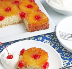 This photo shows us a slice of the pineapple upside down cake from scratch with the rest of the beautiful cake in the background.