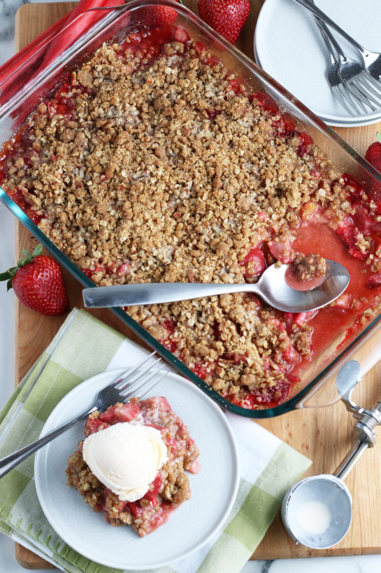 Overhead shot of Strawberry & Rhubarb crisp recipe finished in the pan and out of the oven and plated with a scoop of vanilla ice cream on top.