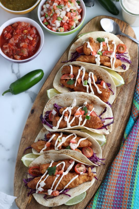 Baja Fish Tacos recipe: beer-battered white fish is nestled inside a warm tortilla with a chipotle lime crema for an island-inspired recipe that will make you feel like you’re on vacation! These tacos are the perfect late summer dinner.