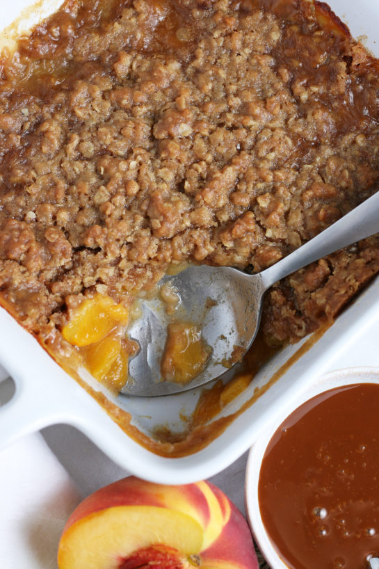 Taking a scoop out of the pan of the Fresh Peach Crisp that is super easy to make! 