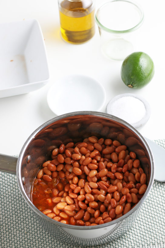 Adding the pinto beans to the pot for cooking the homemade refried beans