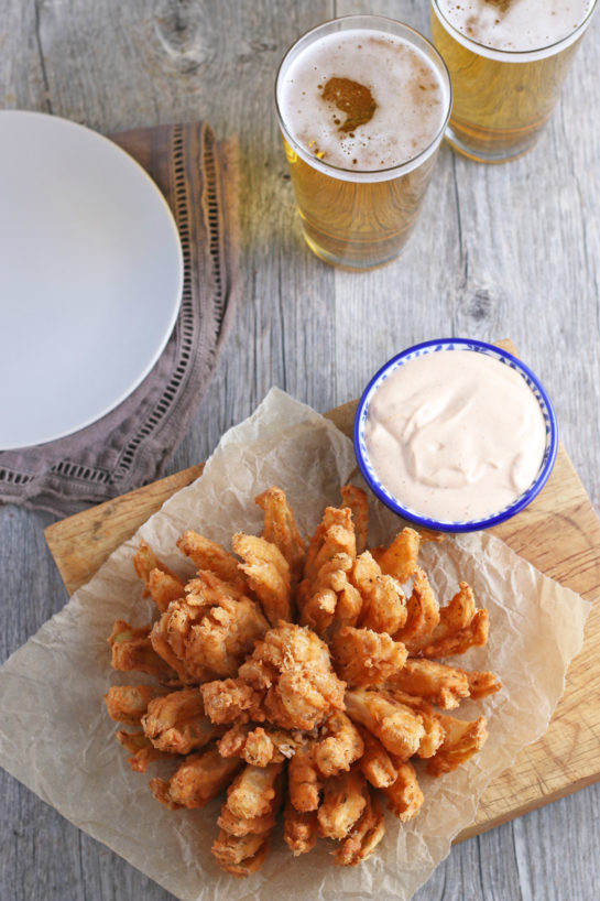 Overhead shot of the Fried Blooming Onion with a homemade dipping sauce is the ultimate appetizer recipe. Grab a sweet onion and turn it into a, incredibly delicious appetizer!