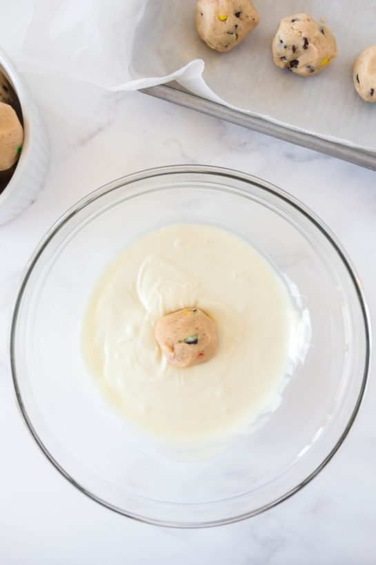 Dipping the dough balls in the white chocolate for Edible Cookie Dough Bombs recipe