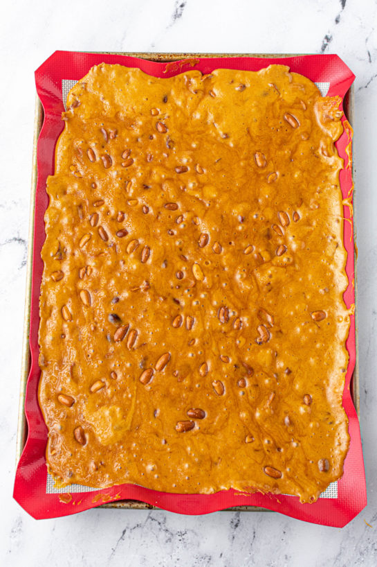 Spreading the mixture on the baking pan to make the Microwave Peanut Brittle recipe