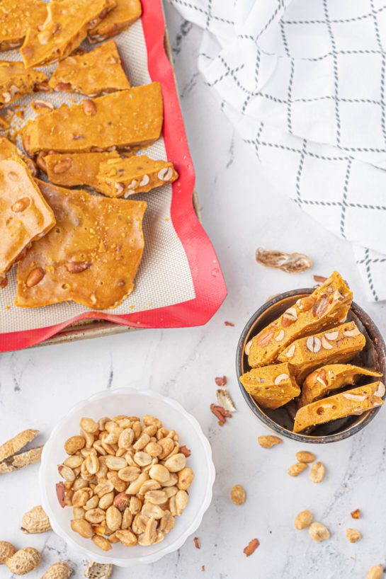 Breaking apart the pieces of brittle on the baking pan to make the Microwave Peanut Brittle recipe