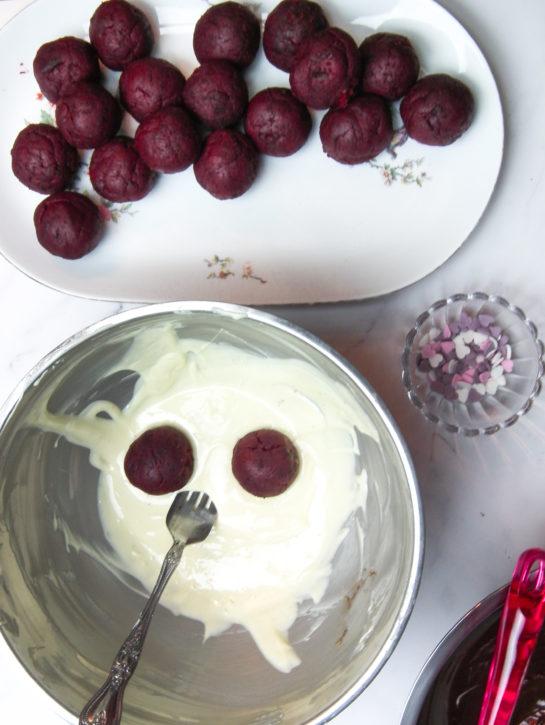 Dipping the truffles in the white chocolate to make the red velvet truffles recipe