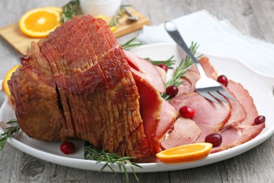 Side shot of the plated Glazed Spiral Ham recipe with a sweet glaze uses a fully-cooked ham and is a great centerpiece for your Christmas, Easter, or Thanksgiving dinner table! The flavor and texture will be a show-stopper!