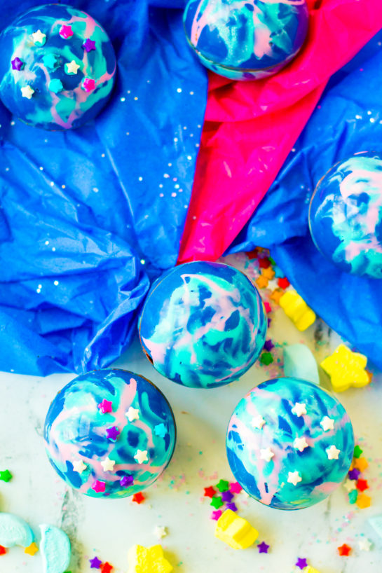 Galaxy Hot Chocolate Bombs are fun, colorful chocolate orbs filled with hot cocoa mix, marshmallows, and sprinkles. This recipe for hot chocolate bombs is an over-the-top way to level up your hot chocolate game, especially for a birthday party!