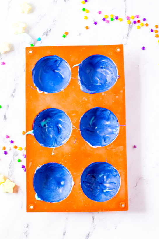 Overheard shot of the silicone molds with the blue melted chocolate for the Galaxy Hot Chocolate Bombs recipe 