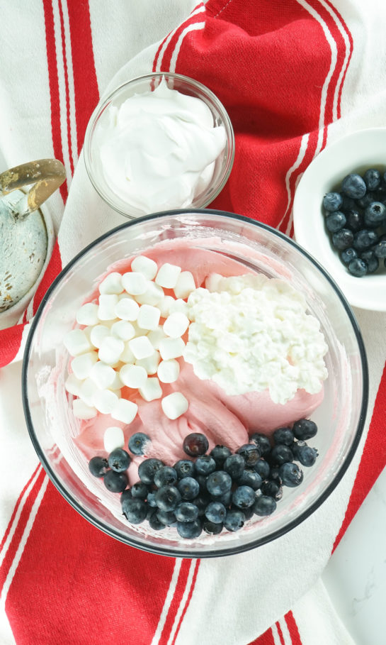 Adding in the blueberries and marshmallows needed to make the Red White and Blue Fluff Salad recipe