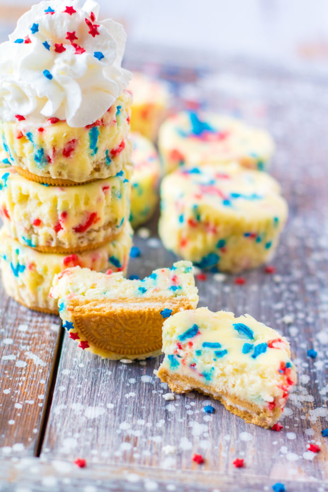 Red, White, and Blue Mini Cheesecakes recipe layered with a Golden Oreo crust and creamy tangy cheesecake. Top with sprinkles and whipped cream for the perfect patriotic dessert for 4th of July!