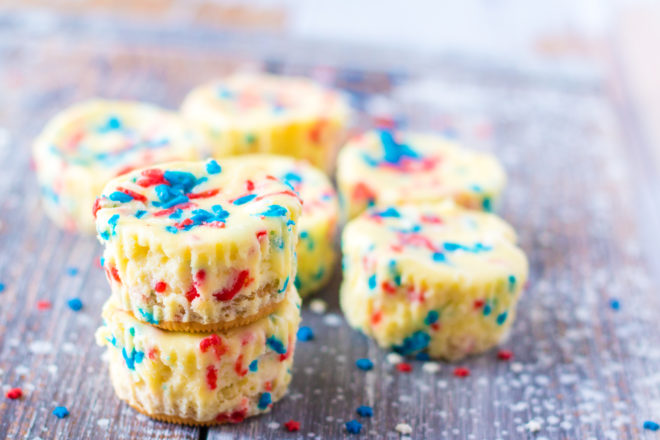 Mini Red, White, and Blue Cheesecakes recipe layered with a Golden Oreo crust and creamy tangy cheesecake. Top with sprinkles and whipped cream for the perfect summer dessert!