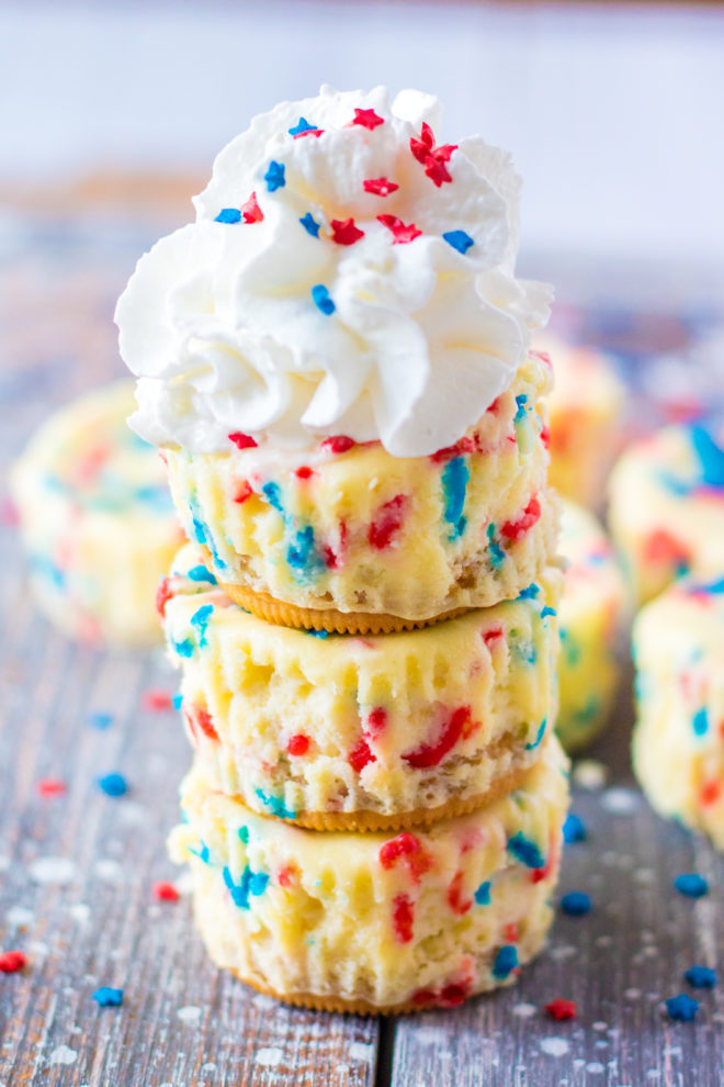 Mini Red, White, and Blue Cheesecakes recipe layered with a Golden Oreo crust and creamy tangy cheesecake. Top with sprinkles and whipped cream for the perfect patriotic dessert for 4th of July!