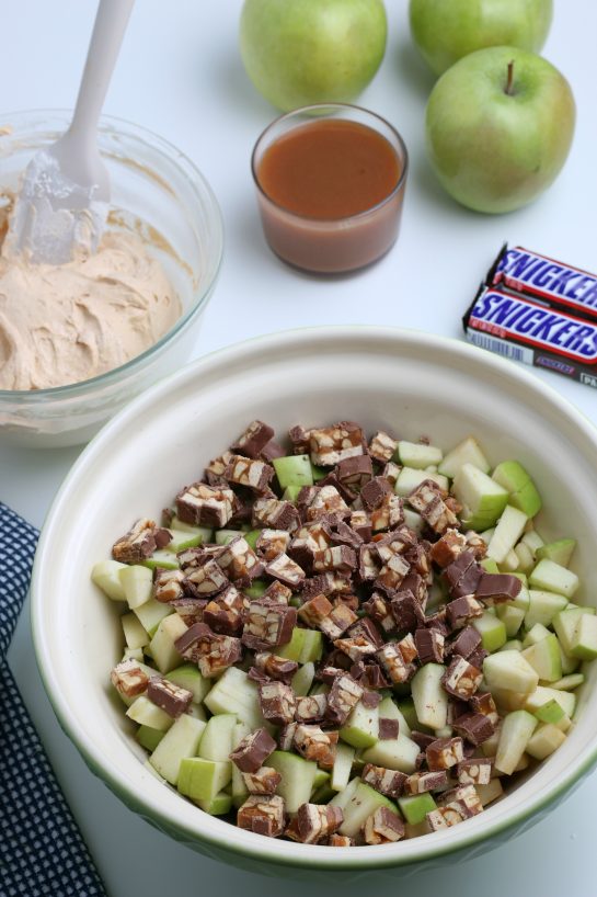 Mixing the chopped up snickers with the apples for the Caramel Apple Snickers Salad