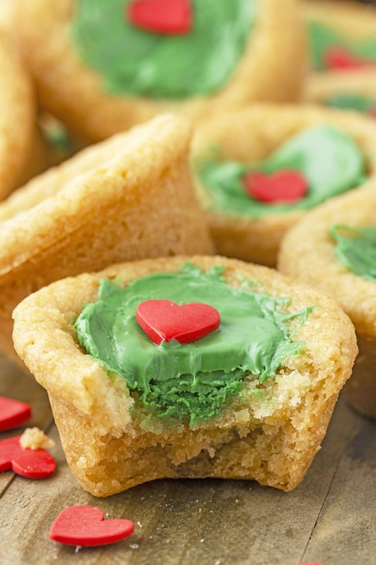 Grinch Cookie Cup Bites recipe is inspired by Dr. Seuss’s How the Grinch Stole Christmas book/movie! They are chewy sugar cookies that have been colored green and adorned with a red heart for a fun holiday dessert! 