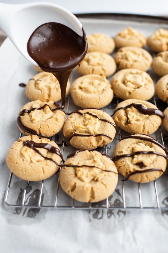 Drizzling the chocolate ganache for the Peanut Butter Thumbprint Cookies recipe 