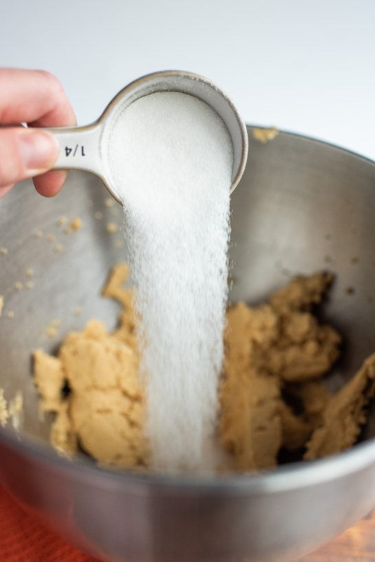 Pouring in the sugar needed for the Peanut Butter Thumbprint Cookies recipe 