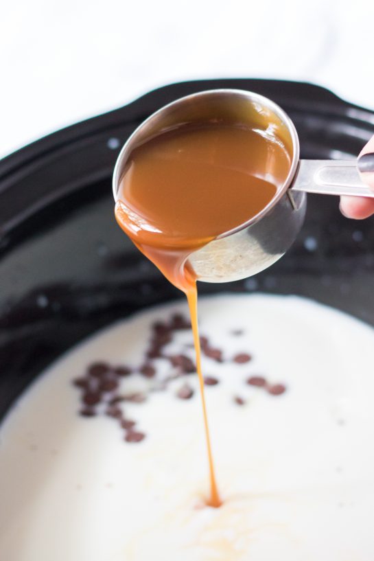 Pouring in the caramel for the Crock Pot Caramel Hot Chocolate holiday recipe