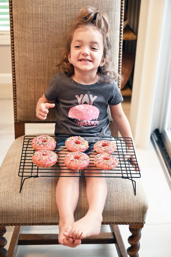 Photo of my daughter holding the completed Vanilla-Glazed Baked Donuts recipe