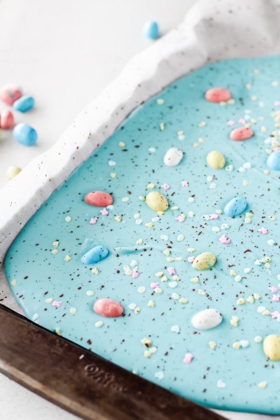 Placing the sprinkles and Robin Eggs onto the blue melting chocolate discs for the No-Bake Robin Egg Easter Bark recipe 
