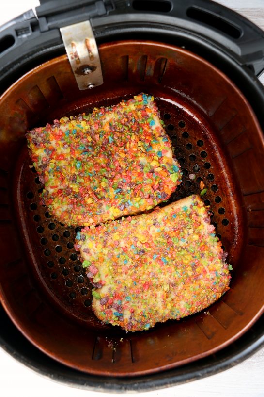 Putting the prepared bread in the air fryer for the Air Fryer Fruity Pebble French Toast recipe