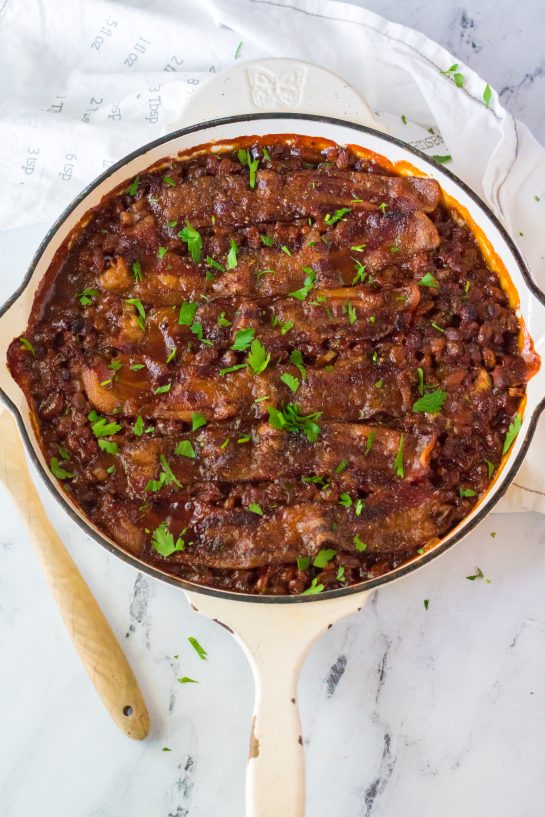 Easy Beefy Baked Beans are my favorite side dish recipe! Beans get mixed with ground beef, onion and bell pepper, brown sugar, ketchup, mustard and Worcestershire before getting topped with a peppered brown sugar bacon.