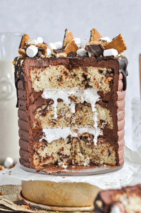 Easy and delicious! This s’mores cake is everything s’mores in a slice. A doctored cake mix full of butter cookies, marshmallow fluff, and chocolate frosting!