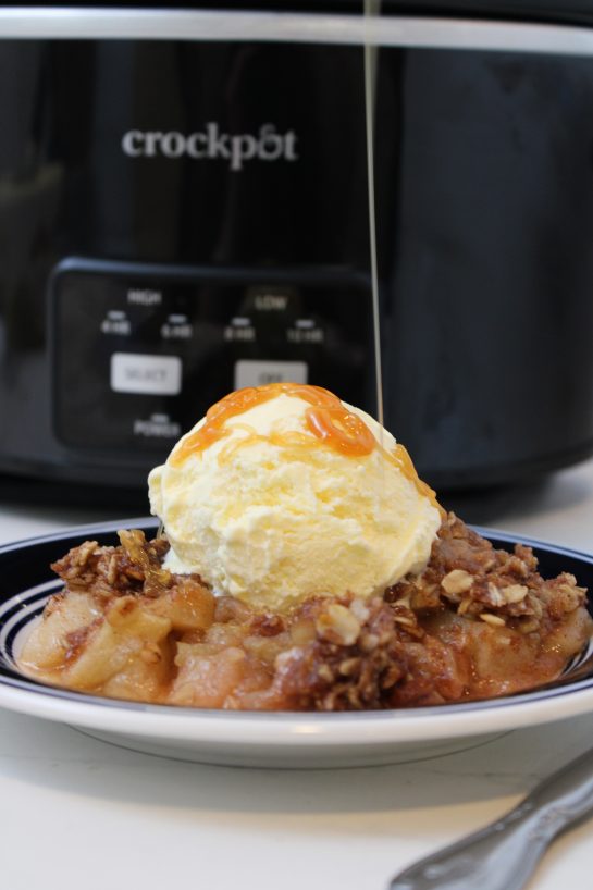 Pouring the caramel topping onto the finished Crock Pot Apple Crisp recipe