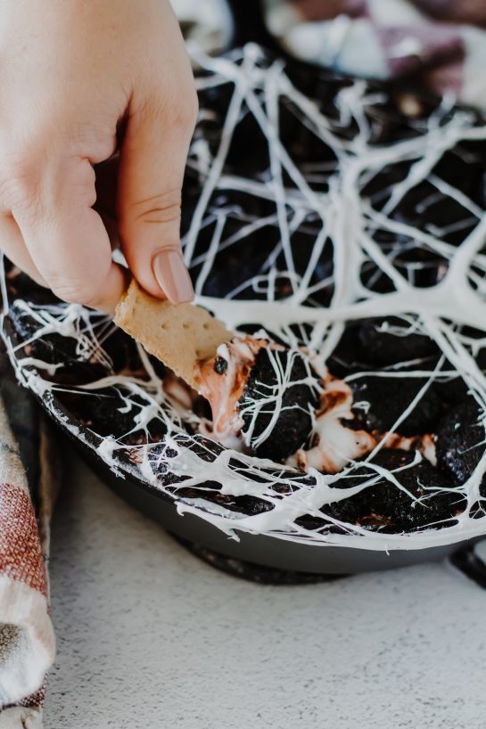 Spiderweb S'mores Dip recipe needs only a few ingredients, takes minutes to make, and is a super-fun Halloween party food idea! Creamy melted white chocolate topped with toasted marshmallows served with graham crackers, cookies, pretzels or fruit for dipping.