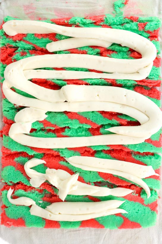 Piping the frosting onto the baked cake in the jelly roll pan to make this Christmas cake roll recipe