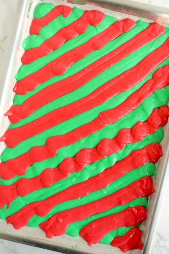 Piping the cake batter into the jelly roll pan to make this Christmas cake roll recipe