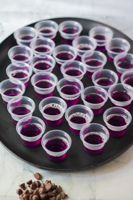 The Halloween Jello Shots recipe being made with the purple layer being poured into the plastic cups